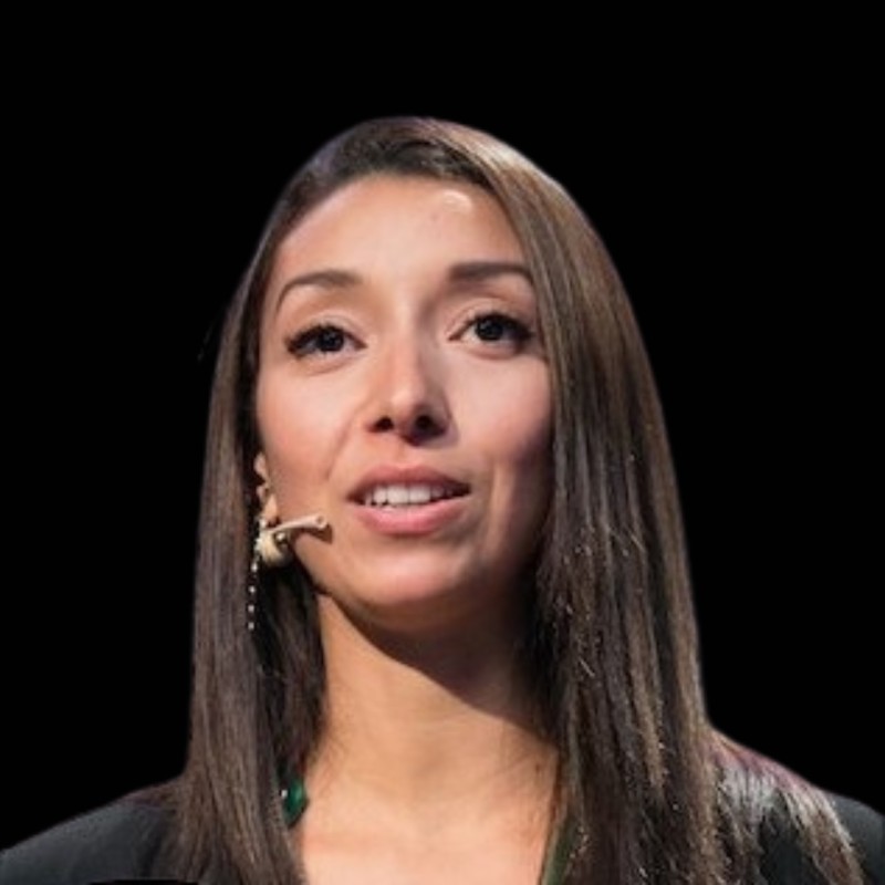 Raja Skogland, NorBAN board member, speaking on stage with a headset microphone